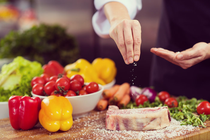 chef putting salt on a juicy slice of raw steak